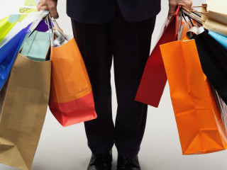 Mature man holding assorted shopping bags, low section