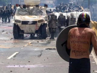A protester faces the National Guard during clashes May 10 in Caracas, Venezuela. The motto on his back reads: "Mom, today I went out to defend Venezuela. If I do not come back, I went with her." Latin American bishops will discuss the evolving political crisis in Venezuela during a four-day long assembly in El Salvador. (CNS photo/Miguel Guitierrez, EPA) See CELAM-VENEZUELA May 10, 2017.