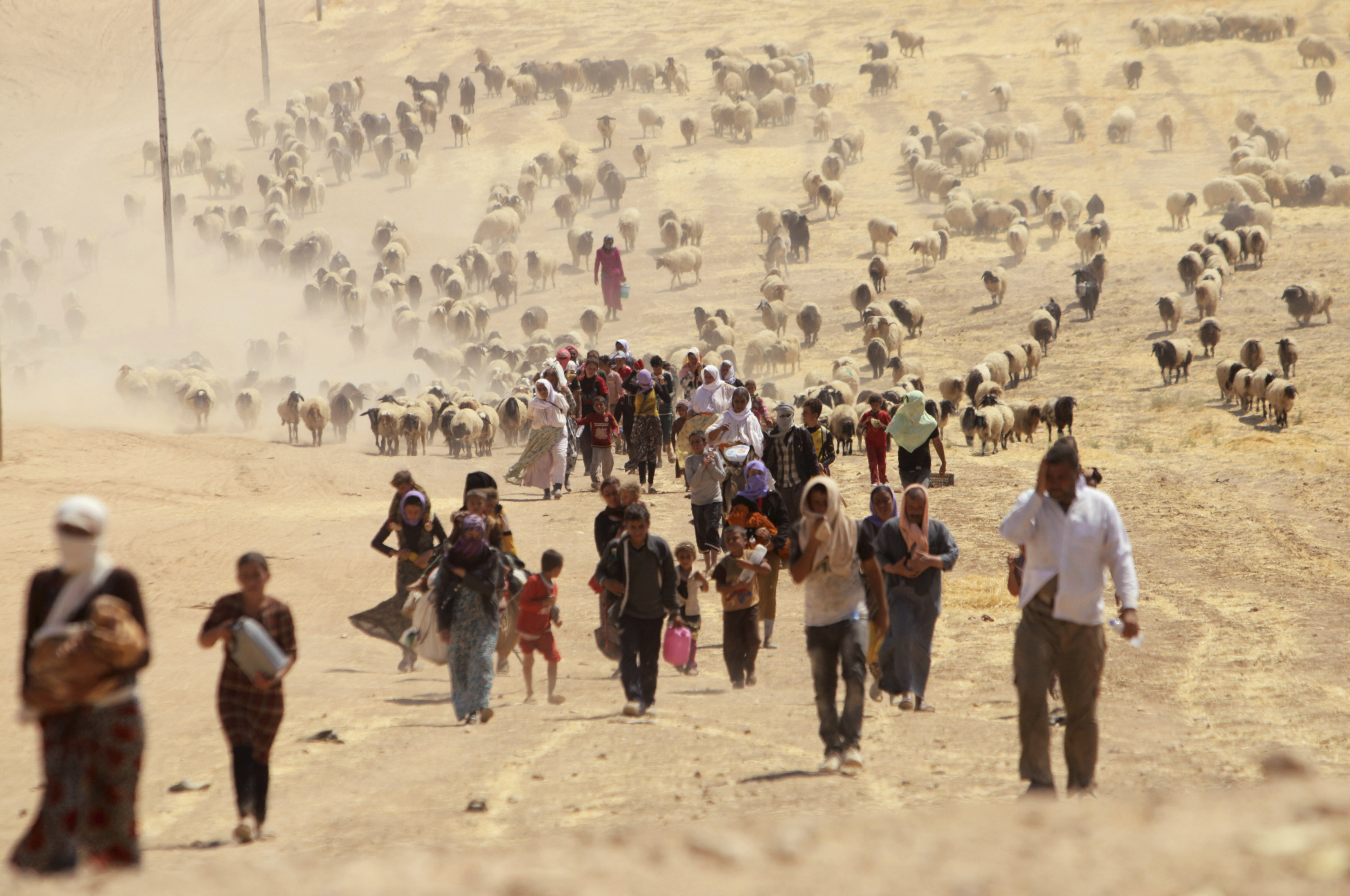 Displaced people from the minority Yazidi sect, fleeing violence from forces loyal to the Islamic State in Sinjar town, walk towards the Syrian border, on the outskirts of Sinjar mountain, near the Syrian border town of Elierbeh of Al-Hasakah Governorate August 10, 2014. Islamic State militants have killed at least 500 members of Iraq's Yazidi ethnic minority during their offensive in the north, Iraq's human rights minister told Reuters on Sunday. The Islamic State, which has declared a caliphate in parts of Iraq and Syria, has prompted tens of thousands of Yazidis and Christians to flee for their lives during their push to within a 30-minute drive of the Kurdish regional capital Arbil. Picture taken August 10, 2014. REUTERS/Rodi Said (IRAQ - Tags: POLITICS CIVIL UNREST CONFLICT TPX IMAGES OF THE DAY) - RTR41YW4