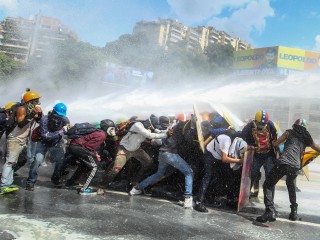 Government protestors in Caracas, Venezuela, are sprayed by a national guard water canon May 29. (CNS photo/Mauricio Duenas, EPA)