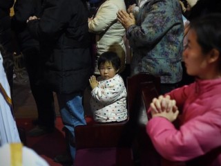 A young Chinese worshipper attends the Christmas Eve mass at a Catholic church in Beijing on December 25, 2014 as Christians around the world prepare to celebrate the holy day.    / AFP PHOTO / WANG ZHAO