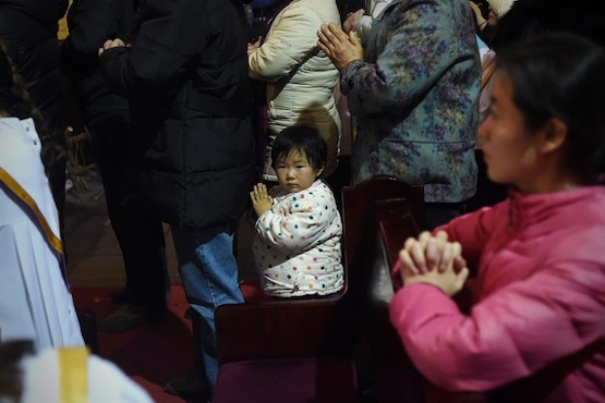 A young Chinese worshipper attends the Christmas Eve mass at a Catholic church in Beijing on December 25, 2014 as Christians around the world prepare to celebrate the holy day. / AFP PHOTO / WANG ZHAO