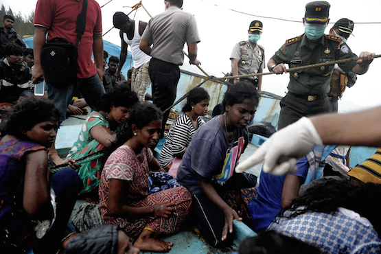 Migrants from Sri Lanka remain on their boat despite their vessel being washed ashore on the west coast of Lhoknga in Aceh Besar, Indonesia's Aceh province on June 14, 2016. Dozens of Sri Lankan immigrants bound for Australia were stranded off Aceh in northwest Indonesia after their boat broke down, local officials said on June 12. / AFP PHOTO / CHAIDEER MAHYUDDIN