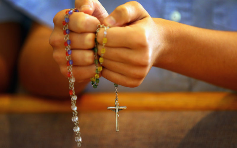 MIAMI, FL - DECEMBER 21: A child holds rosary beads as she prays during a service at St. Rose of Lima School, for the victims of the school shooting one week ago in Newtown, Connecticut on December 21, 2012 in Miami, Florida. Across the country people marked the one week point since the shooting at Sandy Hook Elementary School in Newtown, Connecticut that killed 26 people. (Photo by Joe Raedle/Getty Images)