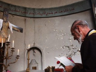 BAGHDAD, IRAQ - OCTOBER 17:  An Iraqi Christian Priest leads a Sunday service at a destroyed Roman Catholic Church October 17, 2004 in Baghdad, Iraq. On Saturday, a series of bombings damaged five churches as part of an escalation in attacking the Christian minority of Baghdad.  (Photo by Marco Di Lauro/Getty Images)