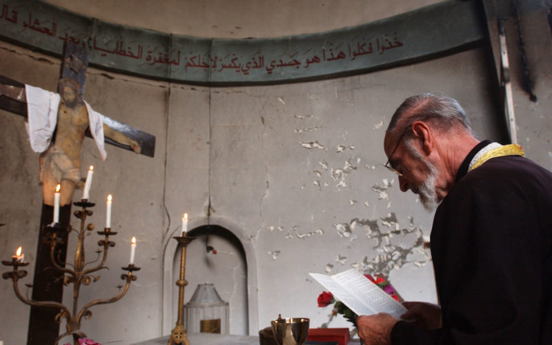 BAGHDAD, IRAQ - OCTOBER 17: An Iraqi Christian Priest leads a Sunday service at a destroyed Roman Catholic Church October 17, 2004 in Baghdad, Iraq. On Saturday, a series of bombings damaged five churches as part of an escalation in attacking the Christian minority of Baghdad. (Photo by Marco Di Lauro/Getty Images)