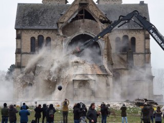 Spectators and journalists look on as the desacralized St Lambertus church in Erkelenz-Immerath, western Germany, is being demolished on January 8, 2018, in order to make possible brown coal surface mining.
Residents from the village of Immerath were relocated previously, as the area is to be exploited by German energy supplier RWE Power in an extension of their Tagebau Garzweiler open pit lignite mine. / AFP PHOTO / dpa / Henning Kaiser / Germany OUT        (Photo credit should read HENNING KAISER/AFP/Getty Images)