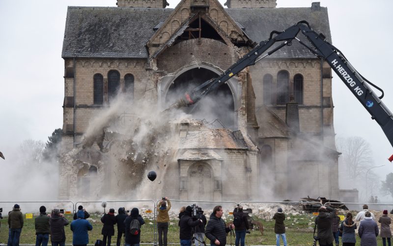 Spectators and journalists look on as the desacralized St Lambertus church in Erkelenz-Immerath, western Germany, is being demolished on January 8, 2018, in order to make possible brown coal surface mining. Residents from the village of Immerath were relocated previously, as the area is to be exploited by German energy supplier RWE Power in an extension of their Tagebau Garzweiler open pit lignite mine. / AFP PHOTO / dpa / Henning Kaiser / Germany OUT        (Photo credit should read HENNING KAISER/AFP/Getty Images)