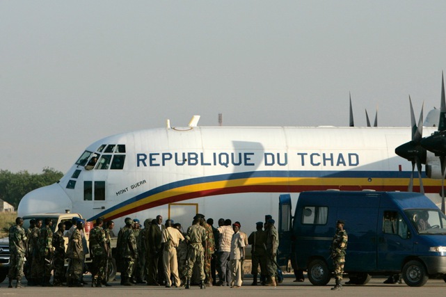 A Chadian military plane transporting European men and women accused of kidnapping 103 African children is surrounded by Chadian security personnel shortly after arriving at a combined French and Chadian military airport in N'Djamena, Chad, Friday, Nov. 2, 2007. The case of Europeans held in the alleged kidnapping of 103 African children should be moved to the capital from a remote eastern city, the Supreme Court ruled Friday. (AP Photo/Karel Prinsloo)