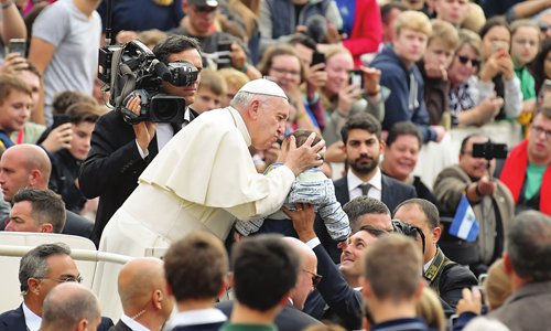 Pope Francis kisses a toddler's head as he arrives on the popemobile car for the weekly general audience on October 17, 2018 at St. Peter's square in the Vatican. (Photo by Tiziana FABI / AFP)