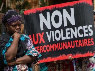 Women hold a placard with an inscription "No to intercommunity violents " during a demonstration on June 22, 2019 in front of the Ouagadougou courthouse to demand "truth and justice" for the victims of Yirgou, a locality in northern Burkina Faso where retaliation against the Fulani community, after a terrorist attack, left 49 dead on January 1st. (Photo by OLYMPIA DE MAISMONT / AFP)