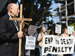Cha Chris Ponnet, giáo sĩ tại Trung tâm St. Camillus ở Los Angeles, phát biểu trong một cuộc biểu tình phản đối án tử hình ở Anaheim ngày 25 tháng 2 năm 2017. (Tín dụng: Andrew Cullen/CNS)