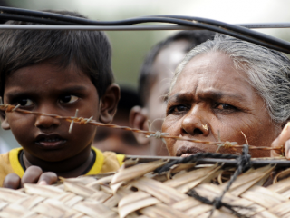 Dân thường bị di dời bởi cuộc nội chiến ở Sri Lanka từ phía sau hàng rào dây thép gai xung quanh trại thực tập của họ ở Vavuniya vào ngày 21 tháng 11 năm 2009. Một báo cáo của Liên Hợp Quốc cho biết những người thiểu số đã phải chịu đựng sự vi phạm tự do tín ngưỡng tôn giáo kể từ khi cuộc xung đột 26 năm kết thúc vào năm 2009 (Ảnh: AFP)