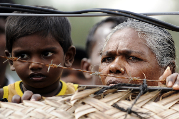 Dân thường bị di dời bởi cuộc nội chiến ở Sri Lanka từ phía sau hàng rào dây thép gai xung quanh trại thực tập của họ ở Vavuniya vào ngày 21 tháng 11 năm 2009. Một báo cáo của Liên Hợp Quốc cho biết những người thiểu số đã phải chịu đựng sự vi phạm tự do tín ngưỡng tôn giáo kể từ khi cuộc xung đột 26 năm kết thúc vào năm 2009 (Ảnh: AFP)