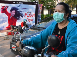 Một phụ nữ đeo mặt nạ giữa những lo ngại về sự lây lan của coronavirus đi xe máy ở Viêng Chăn, thủ đô của Lào, vào ngày 11 tháng 3. Quốc gia nghèo khó này vẫn chưa báo cáo một trường hợp nào về Covid-19. (Ảnh: Mladen Antonov / AFP)