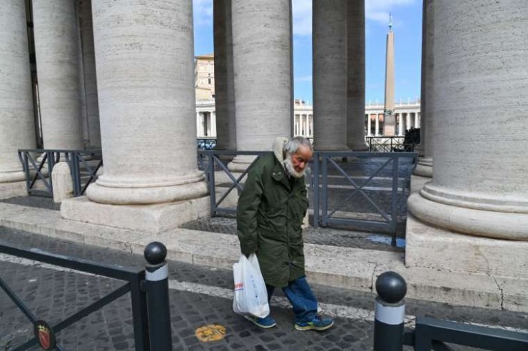 Một người đàn ông vô gia cư lớn tuổi đi bộ dọc theo dãy cột của Quảng trường Thánh Phêrô, ngày 15 tháng 3 năm 2020, vài ngày sau khi quảng trường bị đóng cửa với khách du lịch. Ảnh: Andreas Solaro / AFP