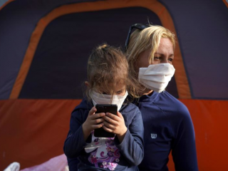 Một người mẹ và con gái đeo mặt nạ bảo vệ đang xin tị nạn ở Hoa Kỳ được nhìn thấy tại một trại di cư ở Matamoros, Mexico, ngày 1 tháng 4 năm 2020, trong đại dịch COVID-19. (Ảnh CNS / Go Nakamura, Reuters)