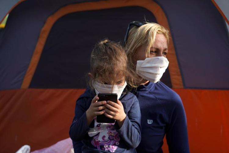 Một người mẹ và con gái đeo mặt nạ bảo vệ đang xin tị nạn ở Hoa Kỳ được nhìn thấy tại một trại di cư ở Matamoros, Mexico, ngày 1 tháng 4 năm 2020, trong đại dịch COVID-19. (Ảnh CNS / Go Nakamura, Reuters)