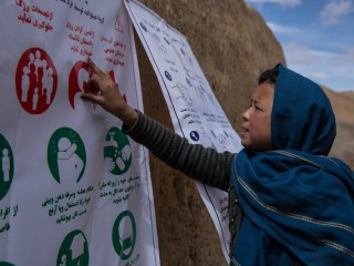 Mina, 11 tuổi, đọc Cảnh báo về các triệu chứng và cách phòng ngừa của COVID-19 coronavirus ở làng Largeurang, Bamyan, Afghanistan. Vào ngày 7 tháng 4 năm 2020 Các Dịch vụ Cứu trợ Công giáo (Tổ chức Thành viên Caritas ở Hoa Kỳ) Nhân viên phân phát Áp phích và Cảnh báo về Dấu hiệu của coronavirus cũng như các cách có thể để ngăn chặn. Ảnh của Stefanie Glinski / Dịch vụ Cứu trợ Công giáo.
 
On 4/7/2020 CRS staff distributed posters and warnings about the signs of the coronavirus as well as possible ways to prevent it.