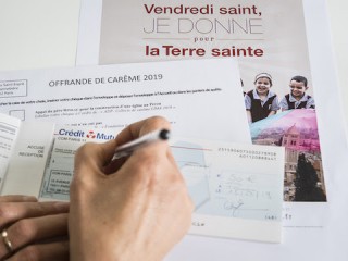 Một người phụ nữ viết một tấm séc để quyên góp trong Mùa Chay, ở Pháp. (Ảnh của CORINNE SIMON / CIRIC)