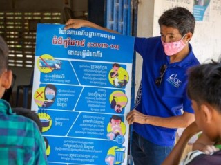 Một nhân viên Dịch vụ Cứu trợ Công giáo ở Campuchia giải thích thông tin mới nhất về COVID-19 cho một nhóm nhỏ các nhà lãnh đạo làng. (Tín dụng: Jennifer Hardy / CRS)