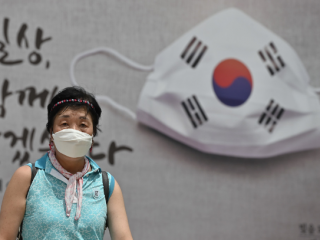 Một phụ nữ đi trước biểu ngữ tại tòa thị chính ở Seoul vào ngày 20 tháng 8 (Ảnh: Jung Yeon-je / AFP)