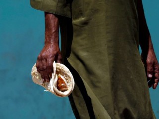 Một người lao động làm công ăn lương hàng ngày ở Pakistan cầm trên tay một gói bánh mì và cà ri truyền thống mà anh ta nhận được từ một điểm phân phát từ thiện trong thời gian cách ly xã hội do Covid-19