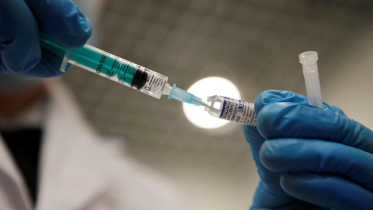 Một nhân viên y tế cầm một ống tiêm vắc-xin Covid-19