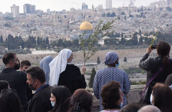 Một nữ tu sĩ cầm cành ô liu khi cô và những người khác dừng lại dọc theo con đường truyền thống mà Chúa Giê-su đã đi trong lần nhập cảnh cuối cùng vào Jerusalem trong lễ rước Chúa nhật Lễ Lá trên Núi Ô-liu ở Jerusalem ngày 28 tháng 3 năm 2020. (Ảnh: Debbie Hill / CNS)