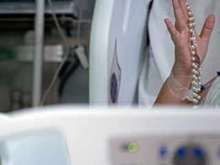 Một bệnh nhân cầm chuỗi hạt Mân Côi (Ảnh: AFP)