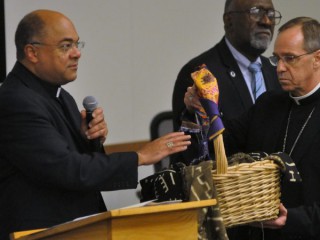 Đức Tổng Giám mục Charles C. Thompson của Indianapolis cầm một chiếc giỏ chứa các bản tường thuật của mọi người về trải nghiệm phân biệt chủng tộc do Đức Giám mục Shelton J. Fabre của Houma-Thibodaux, La., Ở Indianapolis ban phước vào ngày 30 tháng 9 năm 2019. Lời chúc lành của Giám mục Fabre, chủ tịch của Ủy ban Ad Hoc chống Phân biệt chủng tộc của Hội đồng Giám mục Công giáo Hoa Kỳ, đã đến trong một phiên lắng nghe về phân biệt chủng tộc tại Đại học Marian. (Ảnh: Sean Gallagher / The Criterion, qua CNS).