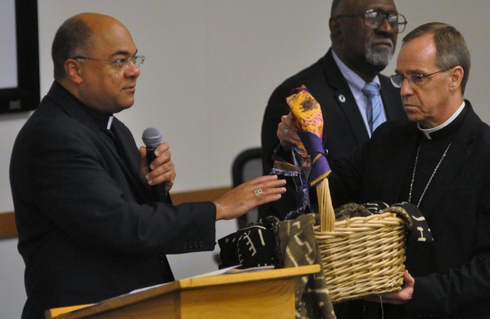 Đức Tổng Giám mục Charles C. Thompson của Indianapolis cầm một chiếc giỏ chứa các bản tường thuật của mọi người về trải nghiệm phân biệt chủng tộc do Đức Giám mục Shelton J. Fabre của Houma-Thibodaux, La., Ở Indianapolis ban phước vào ngày 30 tháng 9 năm 2019. Lời chúc lành của Giám mục Fabre, chủ tịch của Ủy ban Ad Hoc chống Phân biệt chủng tộc của Hội đồng Giám mục Công giáo Hoa Kỳ, đã đến trong một phiên lắng nghe về phân biệt chủng tộc tại Đại học Marian. (Ảnh: Sean Gallagher / The Criterion, qua CNS).