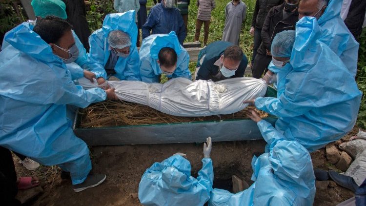 Người thân mặc đồ bảo hộ chôn cất một nạn nhân chết vì Covid-19. (Ảnh: AFP)