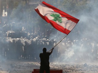Một người biểu tình chống chính phủ vẫy cờ Lebanon trong cuộc đụng độ với lực lượng an ninh ở Beirut ngày 8 tháng 8 năm 2020. (Nguồn: Goran Tomasevic / Reuters qua CNS)