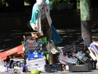 Một cụ già đang tìm kiếm thức ăn trong số các gói thực phẩm đã qua sử dụng ở Milan (ANSA)