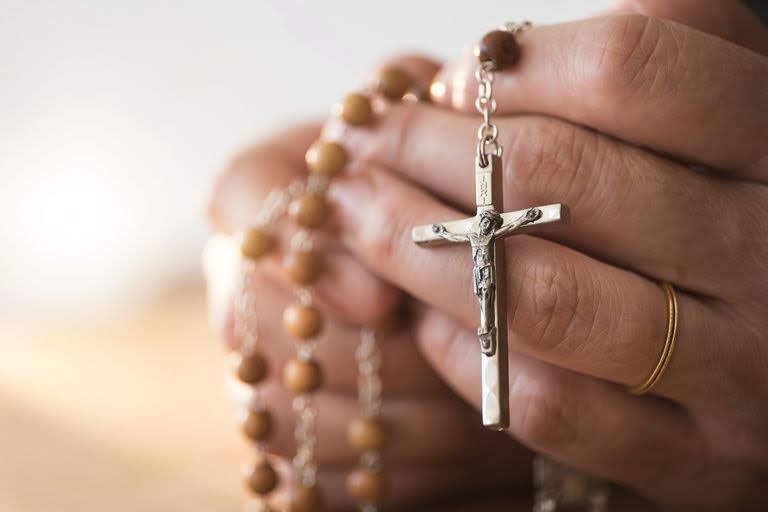 usa--new-jersey--woman-praying-with-rosary-beads-in-hands-580816943-5a9736123418c600367ebf0a