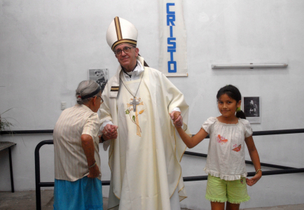 Hồng y người Argentina Jorge Mario Bergoglio nắm tay một phụ nữ và một bé gái trong Thánh lễ Thứ Năm Tuần Thánh năm 2008 tại một nhà thờ ở một khu vực nghèo nàn của Buenos Aires, Argentina, khi ông khai trương Hogar de Cristo đầu tiên, chuyên giúp mọi người chiến đấu với chứng nghiện ngập. (Nguồn: Enrique Garcia Medina / Reuters qua CNS)