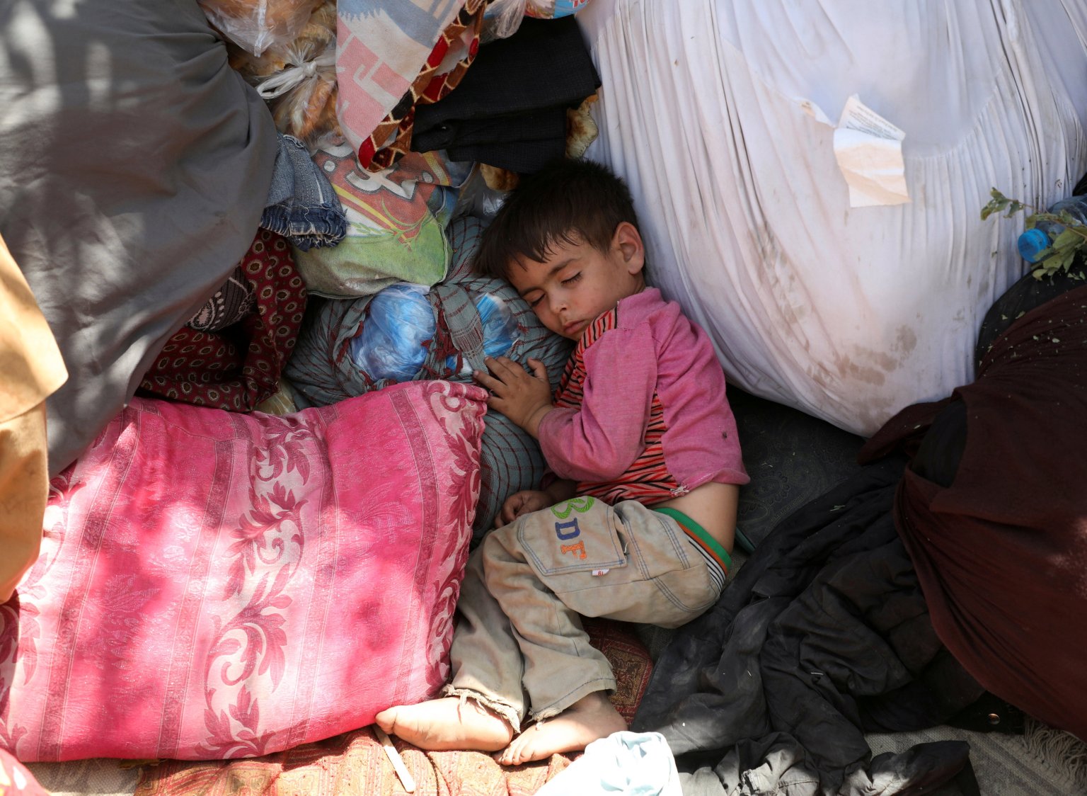 Một đứa trẻ di tản từ các tỉnh phía bắc Afghanistan, chạy trốn cùng gia đình do giao tranh giữa Taliban và lực lượng an ninh Afghanistan, đang ngủ tại một công viên công cộng ở Kabul ngày 10 tháng 8 năm 2021 (Ảnh: CNS photo / Reuters)