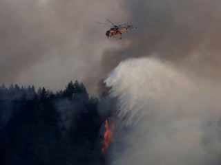2GD2W4A A firefighting helicopter makes a water drop as a wildfire burns in the village of Galatsona, on the island of Evia, Greece, August 10, 2021. REUTERS/Nicolas Economou