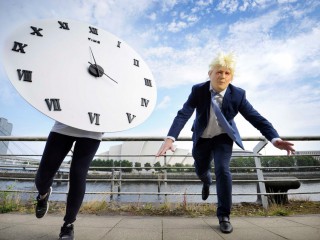 một người mặc trang phục như Thủ tướng Anh Boris Johnson và một người mặc trang phục với chiếc đồng hồ nhằm thu hút sự chú ý về tính cấp bách của cuộc khủng hoảng khí hậu trong sáng kiến "Cuộc chạy đua với thời gian" Glasgow, ngày 16 tháng 8 năm 2021. (Nguồn: Colin Hattersley Photography / Courtesy SCIAF.)