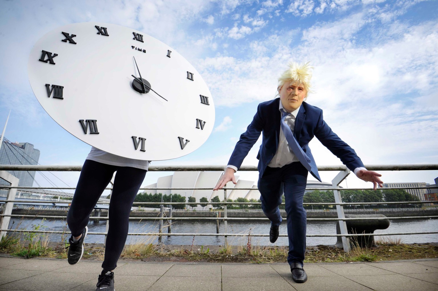 một người mặc trang phục như Thủ tướng Anh Boris Johnson và một người mặc trang phục với chiếc đồng hồ nhằm thu hút sự chú ý về tính cấp bách của cuộc khủng hoảng khí hậu trong sáng kiến "Cuộc chạy đua với thời gian" Glasgow, ngày 16 tháng 8 năm 2021. (Nguồn: Colin Hattersley Photography / Courtesy SCIAF.)