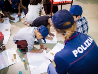 Trẻ em tị nạn Afghanistan đọ sắc cùng một sĩ quan cảnh sát sau khi họ đến sân bay Fiumicino của Rome vào ngày 21 tháng 8 năm 2021, sau khi quân nổi dậy Taliban tiến vào thủ đô Kabul của Afghanistan. (Nguồn: CNS photo / Polizia di Stato/ Reuters)