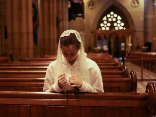 Một phụ nữ trẻ cầu nguyện với chuỗi hạt bên trong Nhà thờ St. Mary ở Sydney vào ngày 6 tháng 1 năm 2021. Sau nhiều năm lên kế hoạch, công việc của ủy ban, sự chấp thuận của Vatican và các phiên lắng nghe, cuộc họp đầu tiên trong số hai phiên họp của Hội đồng Toàn thể sẽ diễn ra vào ngày 3-10 tháng 10 (Ảnh: Loren Elliott / Reuters qua CNS)