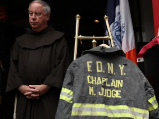 NEW YORK, NY - SEPTEMBER 11: A friar stands near a bunker coat and helmet belonging to FDNY chaplain Mychal Judge during a memorial service and dedication ceremony to induct the two items into the permanent display at the New York City Fire Museum on September 11, 2011 in New York City. New York City firefighters are commemorating the 10th anniversary of the 9/11 terrorist attacks and honoring the 343 firefighters who died in the line of duty.   Justin Sullivan/Getty Images/AFP (Photo by JUSTIN SULLIVAN / GETTY IMAGES NORTH AMERICA / Getty Images via AFP)