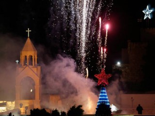 Pháo hoa thắp sáng Nhà thờ Chúa giáng sinh khi người Palestine thắp sáng cây thông Noel tại Quảng trường Manger ở Bethlehem, Bờ Tây, ngày 4 tháng 12 năm 2021. (Ảnh CNS / Mussa Qawasma, Reuters)