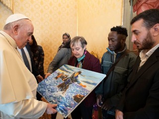 Đức Thánh Cha Phanxicô đang ngắm bức tranh được tặng làm quà sinh nhật bởi một nhóm người xin tị nạn được chuyển từ Síp đến Ý với sự giúp đỡ của ông, trong cuộc gặp tại Vatican ngày 17 tháng 12 năm 2021, sinh nhật của giáo hoàng. Bức tranh vẽ một người tị nạn Afghanistan băng qua Địa Trung Hải cùng với những người nhập cư khác. Những người di cư đang được hỗ trợ bởi Vatican và Cộng đồng Sant’Egidio. (Nguồn: CNS photo / Vatican Media.)
