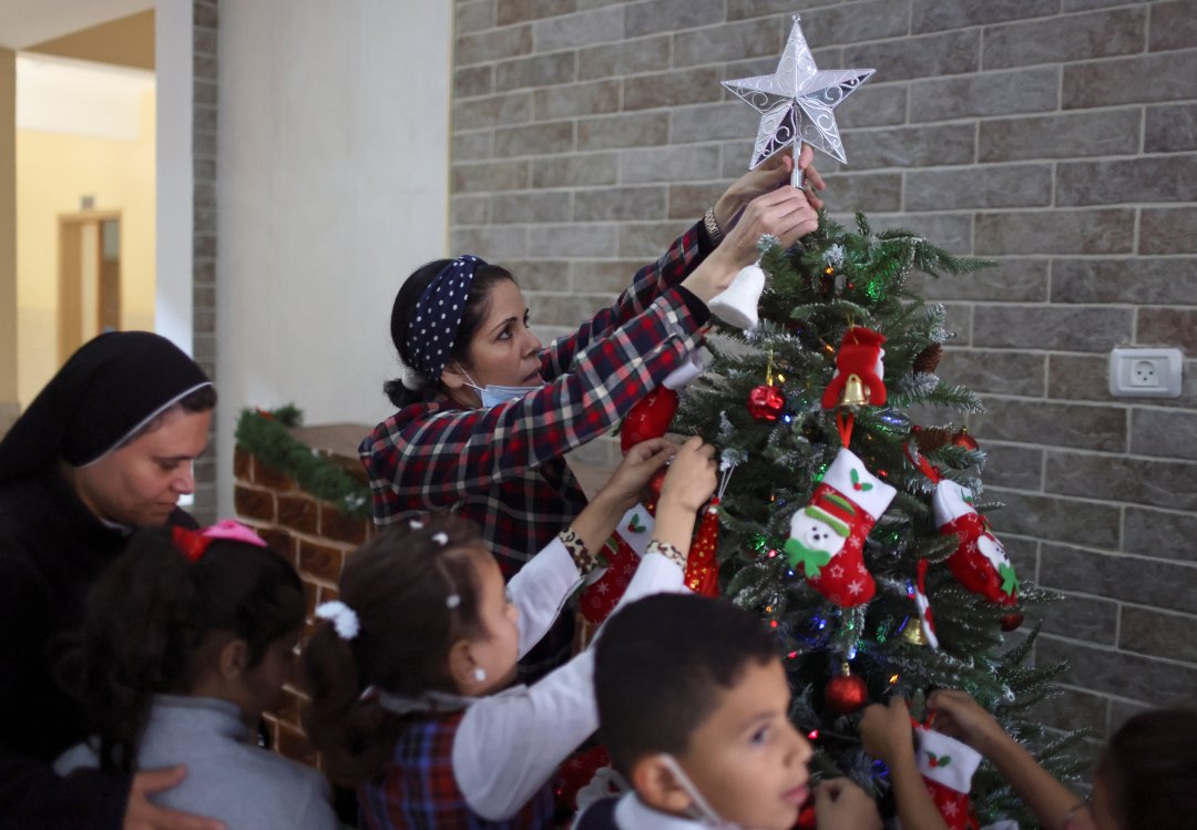 Một giáo viên trang trí cây thông Noel với các học sinh tại trường Rosary Sisters 'ở thành phố Gaza ngày 24 tháng 11 năm 2021. Sami El-Yousef, Giám đốc điều hành của Tòa Thượng phụ Latinh, người vừa tháp tùng Đức Tổng giám mục Pierbattista Pizzaballa trong chuyến thăm Giáng sinh hàng năm với cộng đồng Công giáo Gaza, cho biết mọi người trong cộng đồng tràn đầy hy vọng và khả năng phục hồi trong năm nay. (Tín dụng: Mohammed Salem / Reuters qua CNS)
