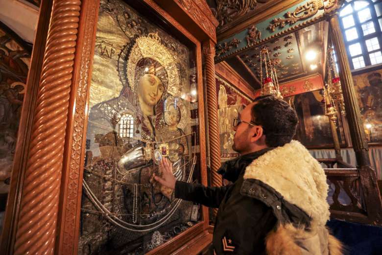 Milad Ayyad, một Kitô hữu Chính thống giáo Hy Lạp gốc Palestine từ Gaza, chạm vào biểu tượng Đức Trinh Nữ và Hài Nhi để được ban phước tại Vương cung thánh đường Hy Lạp ở Nhà thờ Chúa Giáng sinh, nơi truyền thống của Chúa Kitô, trong kinh thánh thành phố Bethlehem ở phía Tây bị chiếm đóng Ngân hàng vào ngày 26 tháng 12 năm 2021 (Ảnh: AFP)