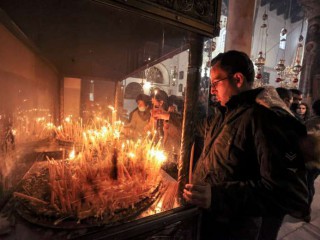 Milad Ayyad, một tín đồ Cơ đốc giáo chính thống Hy Lạp gốc Palestine từ Gaza, thắp nến tại Vương cung thánh đường Hy Lạp ở Nhà thờ Chúa giáng sinh, nơi truyền thống sinh ra của Chúa, ở thành phố Bethlehem trong Kinh thánh ở Bờ Tây bị chiếm đóng vào ngày 26 tháng 12 năm 2021 (Ảnh : AFP)