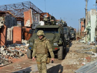 Các thành viên của lực lượng vũ trang Ukraine lái xe quân sự đi qua các tòa nhà bị phá hủy trên ranh giới ngăn cách với phiến quân thân Nga ở Shyrokyne, Ukraine, ngày 21 tháng 4 năm 2021 (Ảnh: Oleksandr Klymenko / Reuters qua CNS)